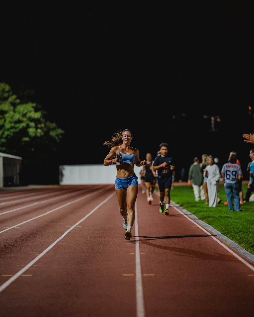 A runner alone on the home straight at night